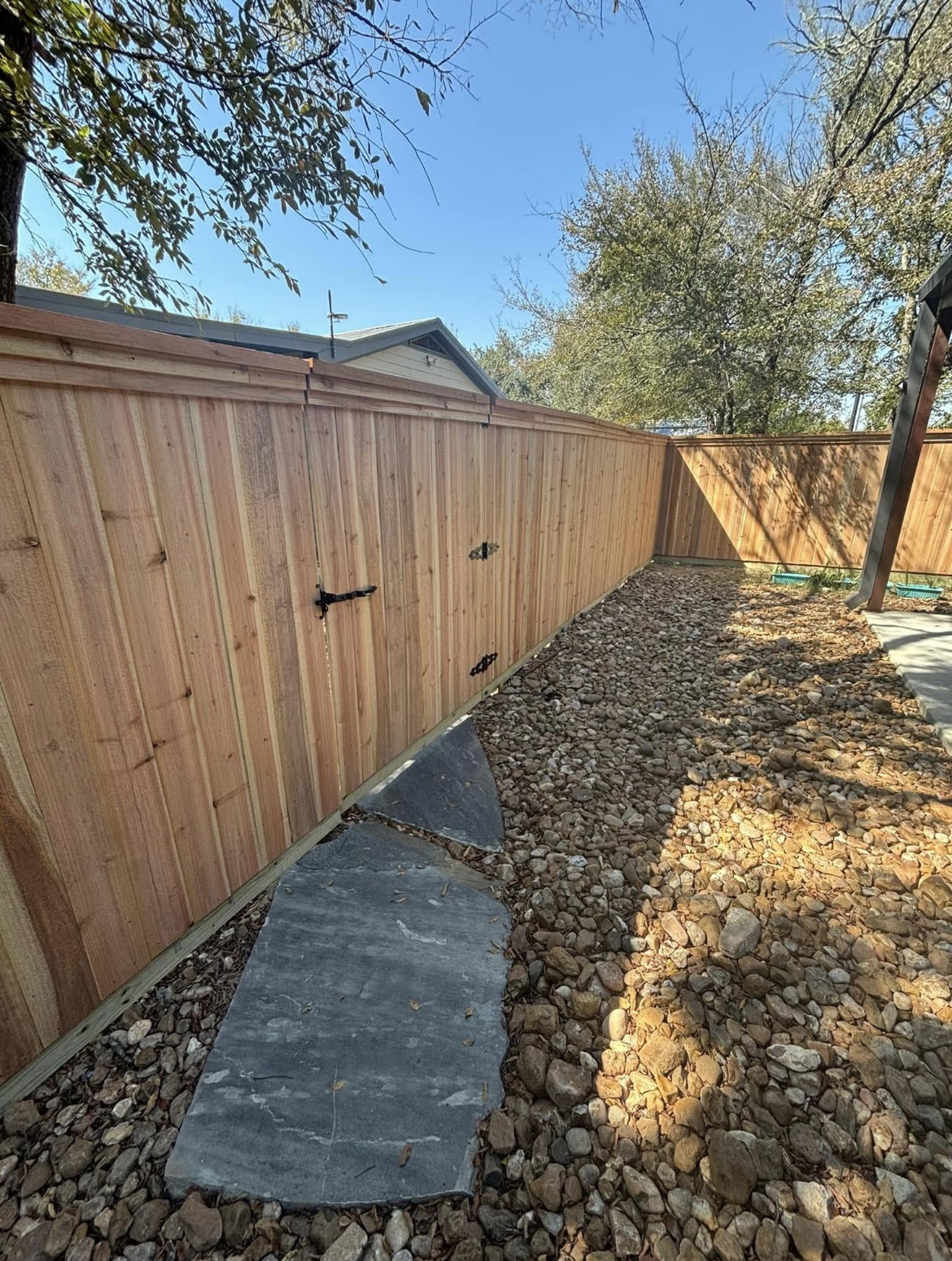 Cedar privacy fence with a gate and flagstone path built by Tejas Construction