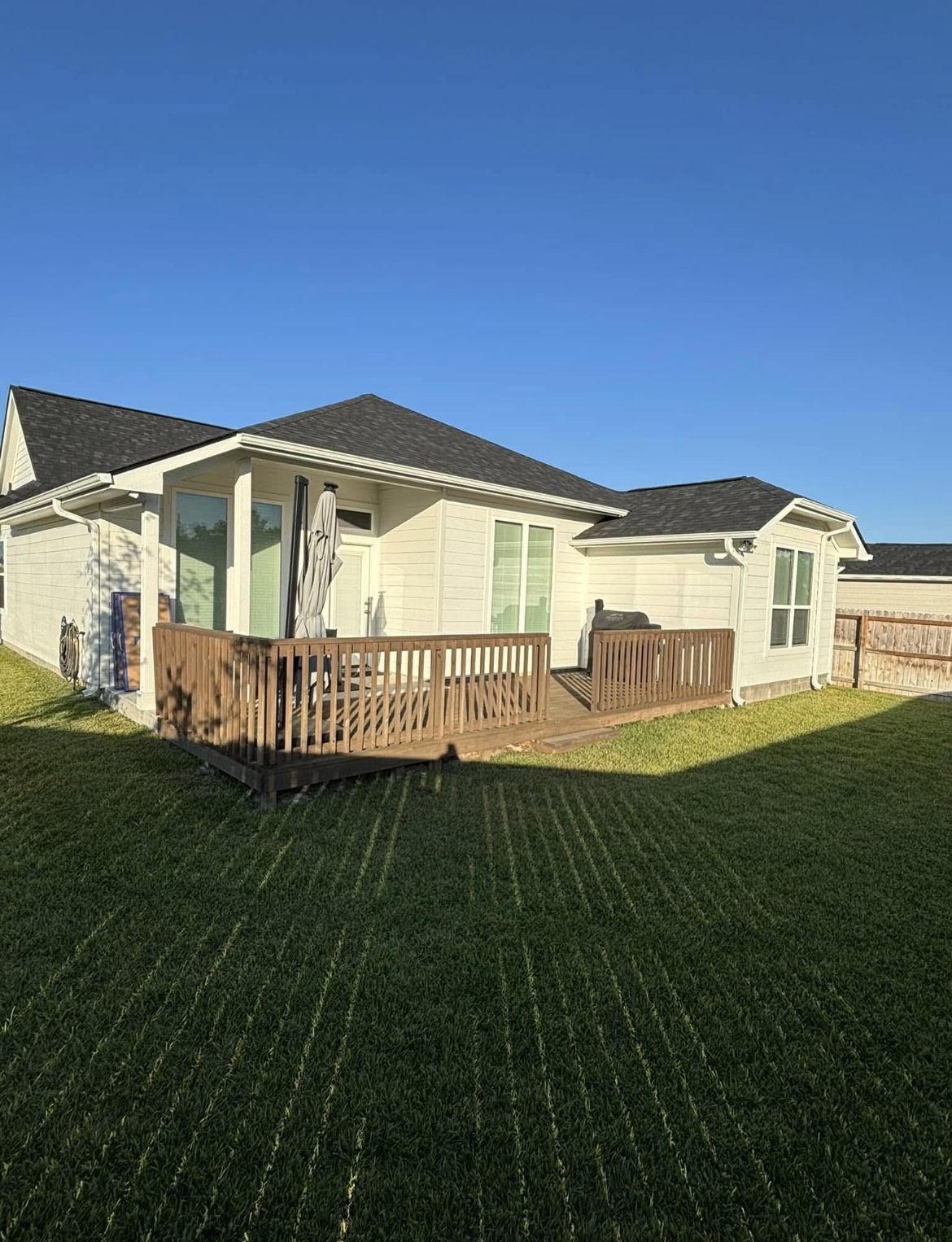 Wood deck with railing wrapping the back of a white farmhouse