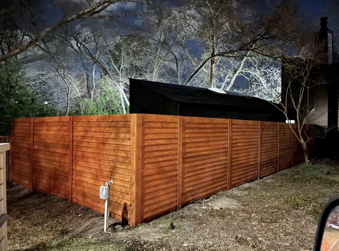 Custom horizontal cedar privacy fence stained a warm honey tone, built by Tejas Construction in the Brazos Valley